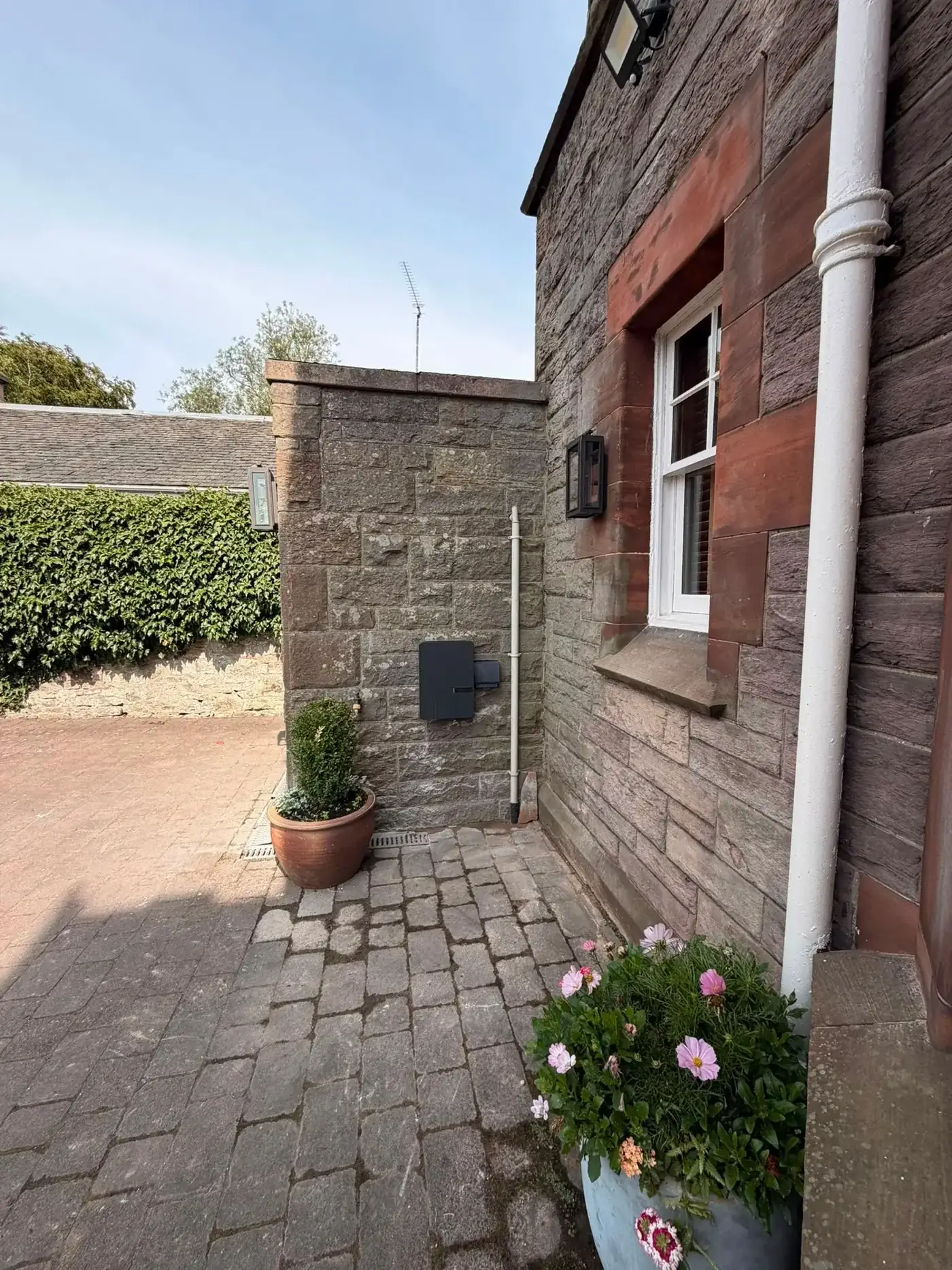 EV charger fitted to a stone wall with charging cable coiled ready for use