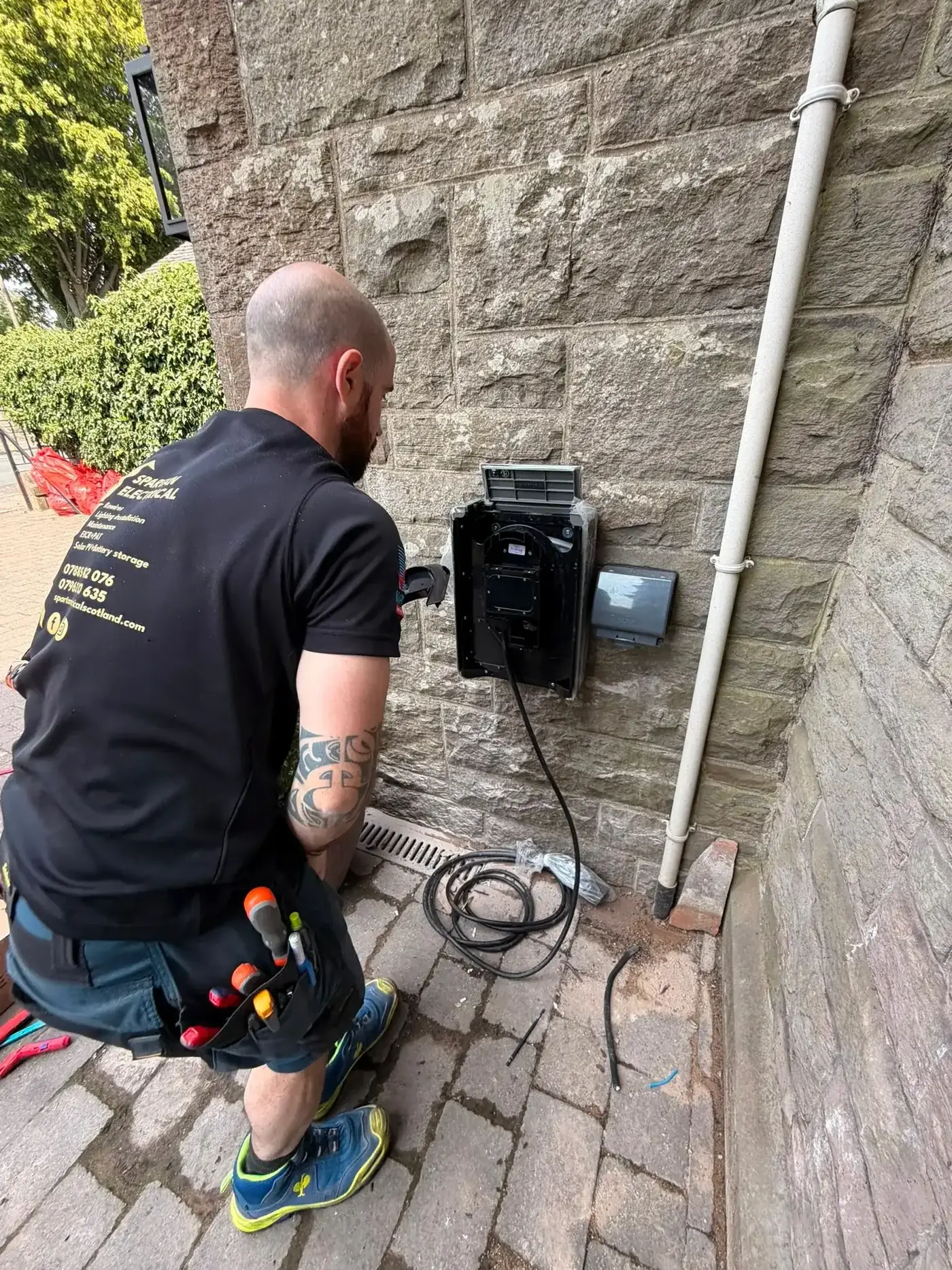 Spartan Electrical engineer installing an EV charger on a stone wall in Edinburgh
