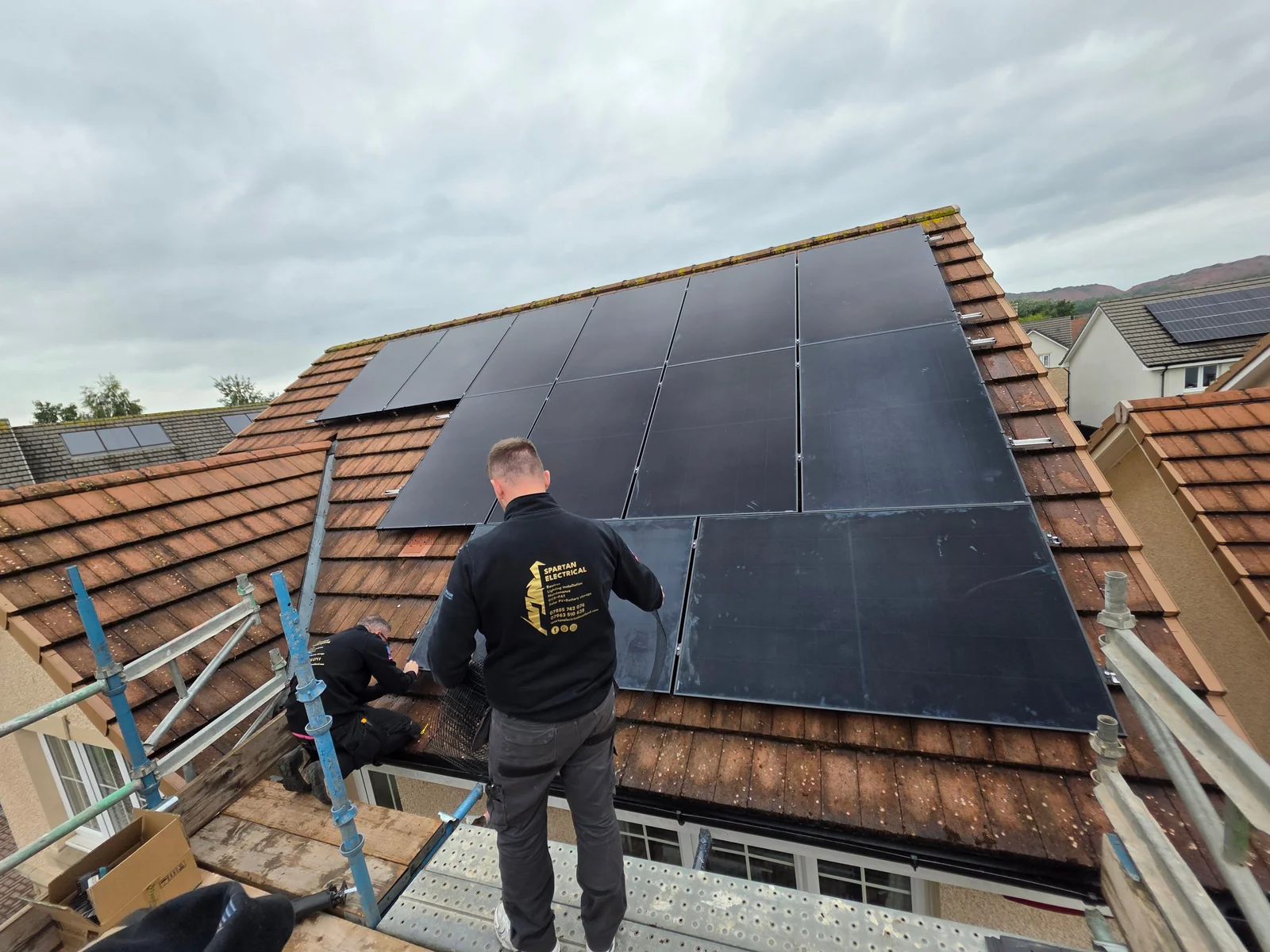 Spartan Electrical team fitting solar panels from scaffold, mid-install